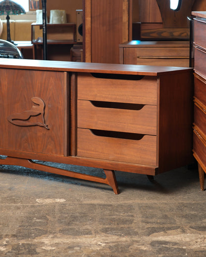 Front corner detail of the sideboard showing three drawers and the carved figural sliding door
