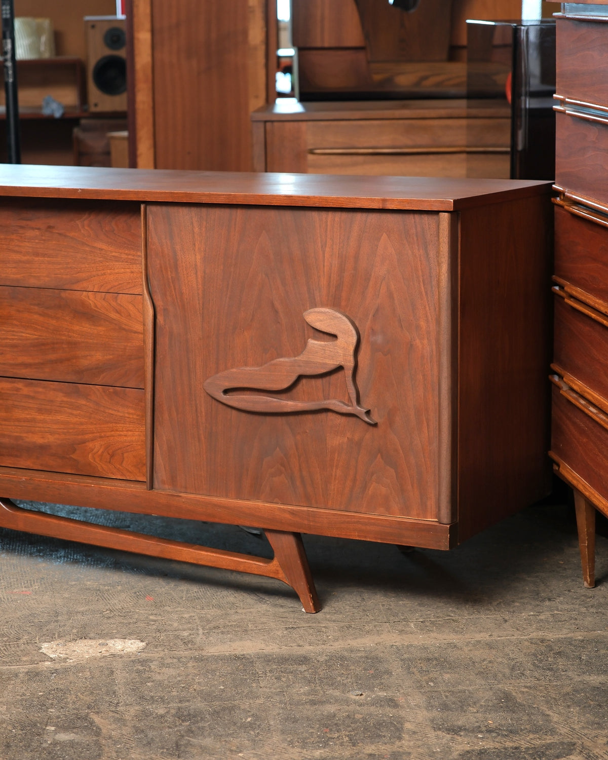 Close-up of the carved figural pull on the walnut sliding door and tapered sculpted leg