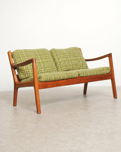 Detail of the teak frame's wood grain and finish along the seat rail.