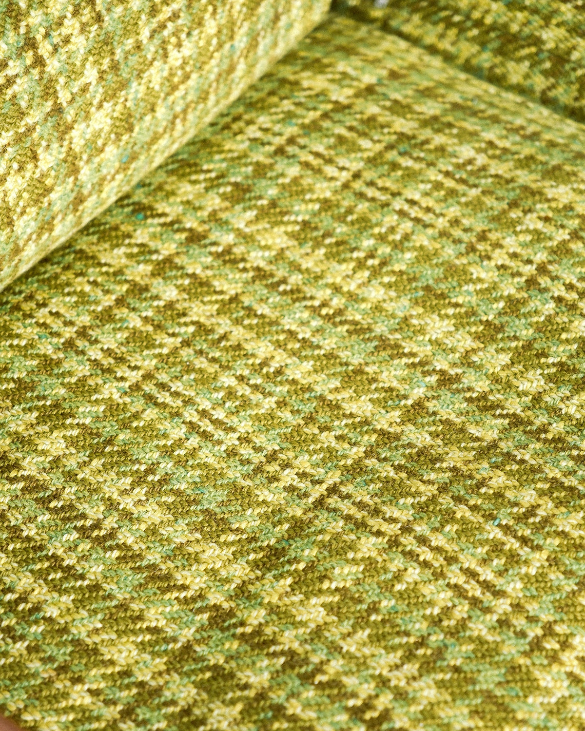 Detail of the green plaid tweed upholstery texture on the sofa cushions.