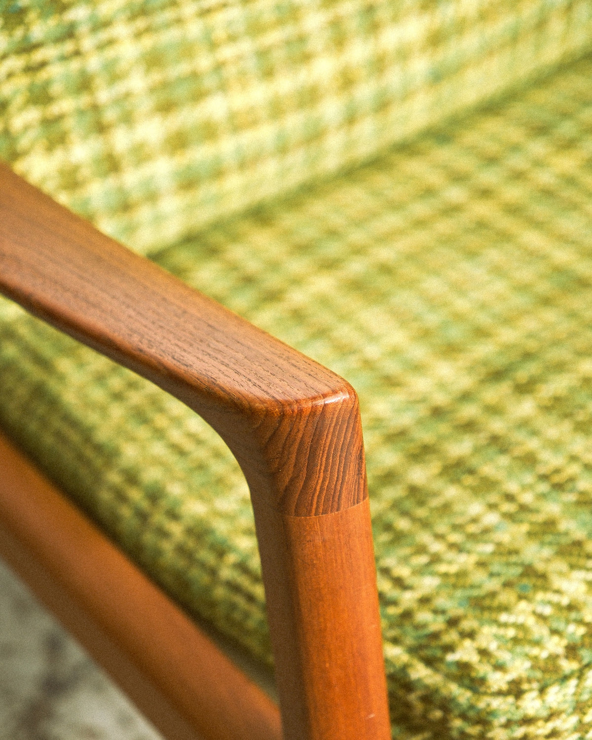 Close-up of the sculpted teak armrest showing joinery and wood grain.