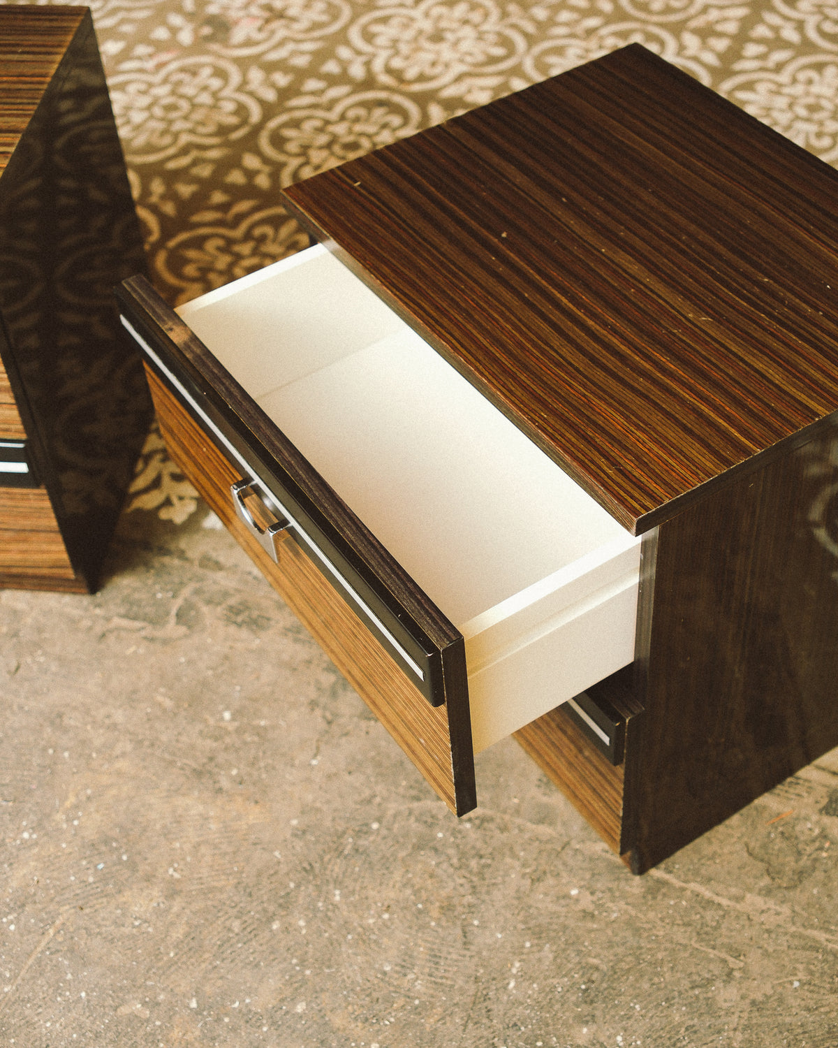 Overhead view of one nightstand with the top drawer open, showing a cream-colored drawer interior.